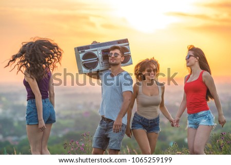 The four people dancing with a boom box on the sunset background