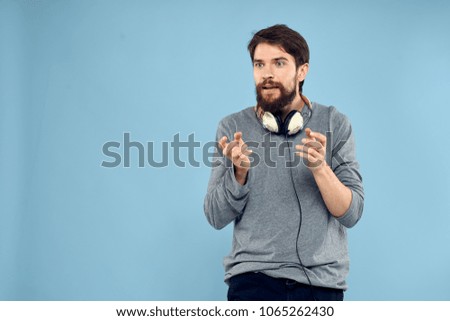  man holds headphones around his neck on a blue background                              