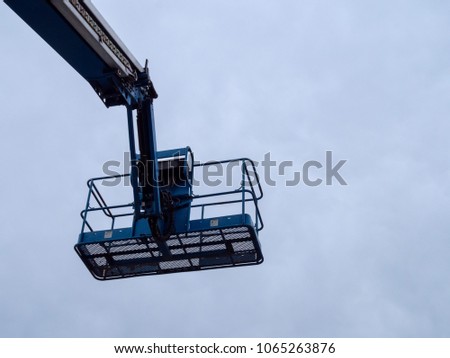 Human carrying basket attached to end of crane on a repair truck