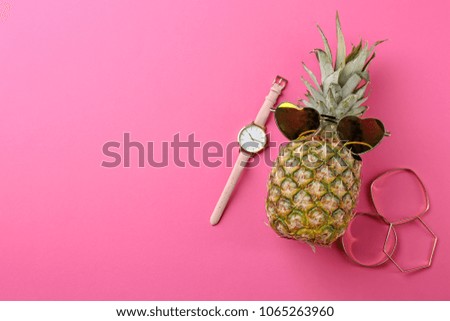 Funny pineapple with sunglasses, bracelets and watch on color background