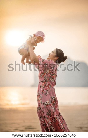 Mother with Little baby happy on the beach, Tropical ocean in Thailand.