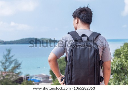 Young man with backpack standing with sea view.