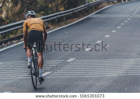 Asian man is cycling road bike. morning ride uphill on the road. Royalty-Free Stock Photo #1065301073