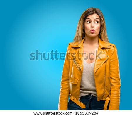 Beautiful young woman happy and surprised cheering expressing wow gesture, blue background