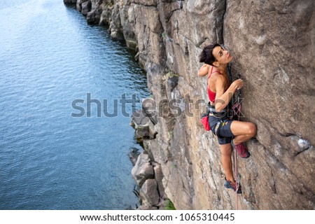 The girl climbs a climbing route over the water. extreme travel. Sport in nature. Royalty-Free Stock Photo #1065310445