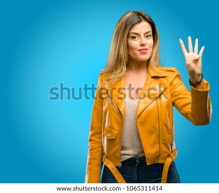 Beautiful young woman raising his finger, is the number four, blue background