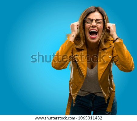 Beautiful young woman stressful, terrified in panic, shouting exasperated and frustrated. Unpleasant gesture. Annoying work drives me crazy, blue background