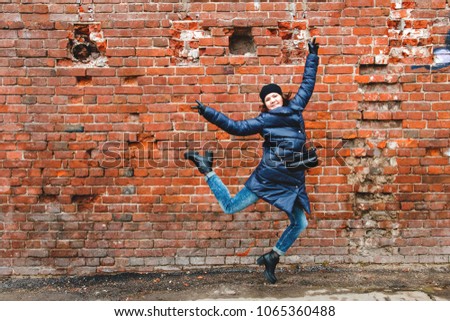 smiling girl was photographed in a jump on a brick wall background.