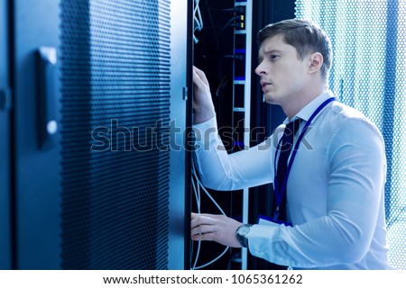 Repairing wires. Concentrated experienced man working in a service cabinet and repairing wires Royalty-Free Stock Photo #1065361262