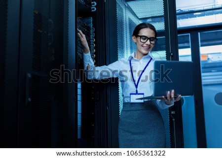 Amazing day. Happy beautiful woman working in a server cabinet and holding her laptop Royalty-Free Stock Photo #1065361322