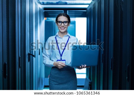 Feeling inspired. Alert young professional woman smiling and holding her laptop Royalty-Free Stock Photo #1065361346