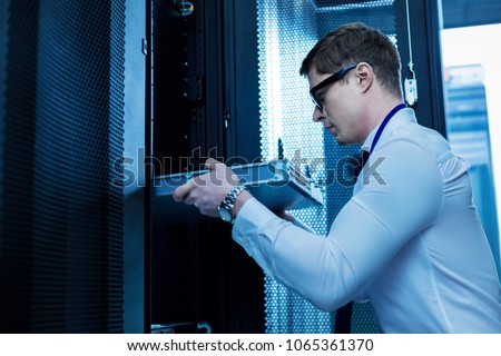 Modern equipment. Serious professional operator working with server equipment in the office Royalty-Free Stock Photo #1065361370