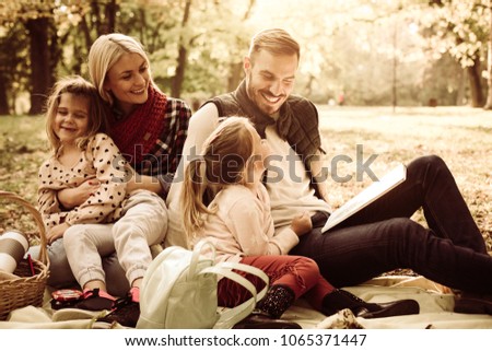 Happy family having picnic. Father teaching daughter to read.