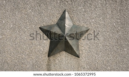 A metal star on a granite wall.