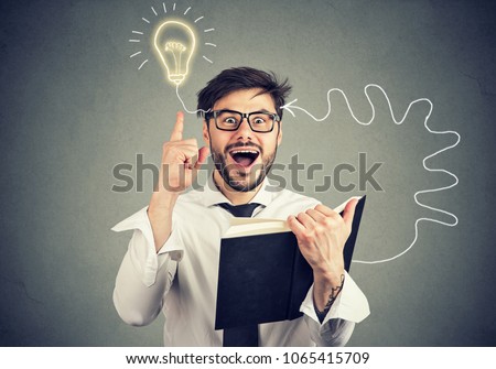 Amazed young man in glasses reading a book comes up with an idea Royalty-Free Stock Photo #1065415709
