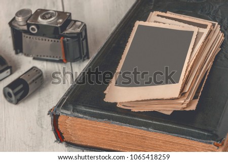 Old photographs and family albums are on the table next to the old camera