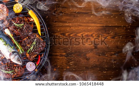 Barbecue garden grill with beef steaks on vintage wooden background.