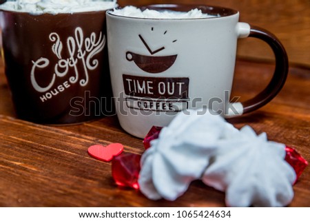 coffee with cream in a brown mug with meringue on a wooden dark background