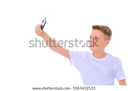 A positive little school boy makes selfie. The concept of photo and video shooting, digital technology. Isolated on white background.
