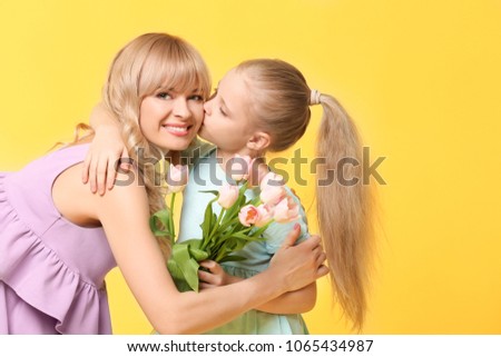 Portrait of cute little girl and her mother with tulip bouquet on color background