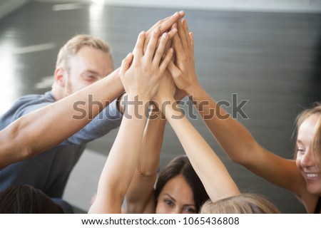 Group of fit happy people giving high five in fitness studio room, talking in a circle after seminar training. Setting goal, achieving team results. Teamwork, mindfulness, active life benefits concept Royalty-Free Stock Photo #1065436808