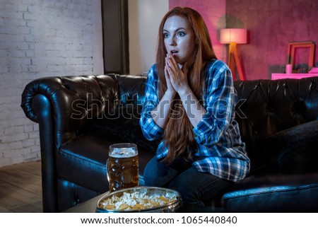 Young woman sport fan watching match drinking beer