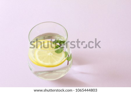 Glass of water, lemon and mint. Glass of pure water, fresh organic lemon and mint isolated on purple background. Detox and healthy food concept. Boost your metabolism concept. Aromatherapy