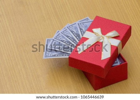 Dollar banknote with red gift box on wooden table background. Business concept