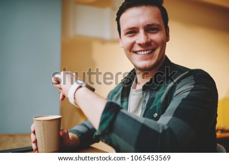 Portrait of cheerful hipster guy wearing modern digital gadget satisfied with portable computer on wrist with useful apps, happy male student looking at camera excited with features of smartwatch