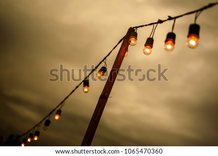 vintage light bulb on string wire against sunset
