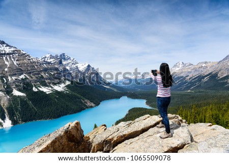 A Tourist woman taking picture by mobile phone of Peyto Lake with mobile phone, Banff National Park, Alberta, Canada