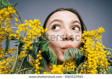 funny cute girl sniffing fragrant yellow mimosa, spring mood
