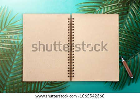 flat lay of green tropical leaf frame and notebook on color background with free copy space for your creativity ideas texts