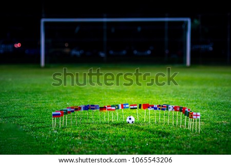 Football ball on green grass and all national flags Royalty-Free Stock Photo #1065543206