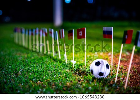 Football ball on green grass and all national flags  Royalty-Free Stock Photo #1065543230