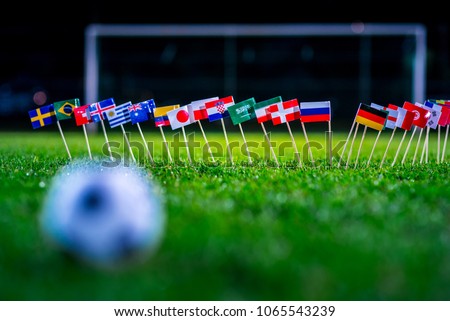 Football ball on green grass and all national flags Royalty-Free Stock Photo #1065543239