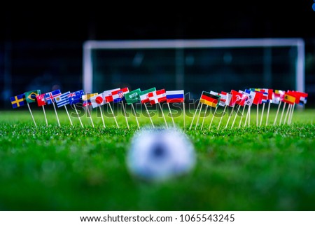 Football ball on green grass and all national flags  Royalty-Free Stock Photo #1065543245