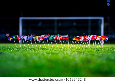 Football ball on green grass and all national flags  Royalty-Free Stock Photo #1065543248