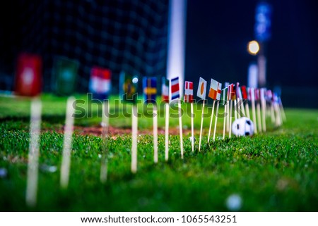 Football ball on green grass and all national flags  Royalty-Free Stock Photo #1065543251