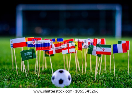 Football ball on green grass and all national flags Royalty-Free Stock Photo #1065543266