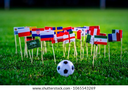 Football ball on green grass and all national flags Royalty-Free Stock Photo #1065543269
