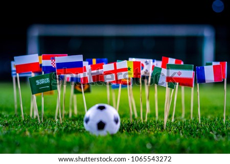 Football ball on green grass and all national flags Royalty-Free Stock Photo #1065543272