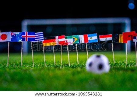Football ball on green grass and all national flags  Royalty-Free Stock Photo #1065543281