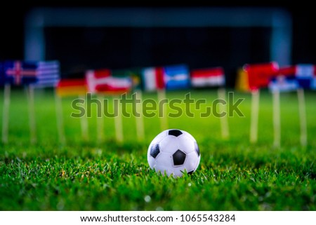 Football ball on green grass and all national flags Royalty-Free Stock Photo #1065543284