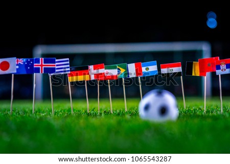 Football ball on green grass and all national flags  Royalty-Free Stock Photo #1065543287