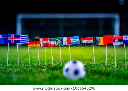 Football ball on green grass and all national flags  Royalty-Free Stock Photo #1065543290