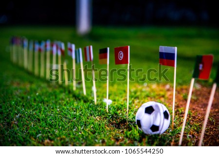 Football ball on green grass and all national flags Royalty-Free Stock Photo #1065544250