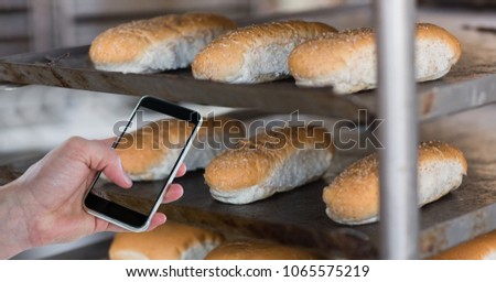 Hand taking picture of breads through smart phone at bakery