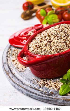 Dry mixture of quinoa grains on wooden background with tomatoes and lemon. Selective focus.