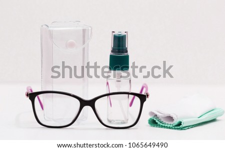 Beautiful eye glasses, black frame, napkins. Liquid cleaning in bottle. White background. Optical vision style. Model woman. Plastic lens close up. Spectacles equipment isolated.